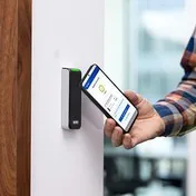 Technician holding a phone running Linq Mobile to an HID Signo reader